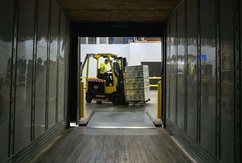Forklift loading pallets into a dry van trailer at a dock