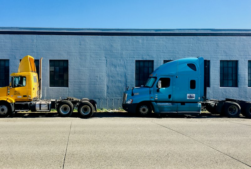 Two semi tractors parked in front of a warehouse building